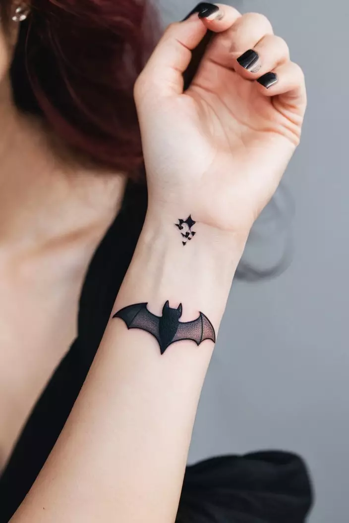 Cute Minimal Bat Tattoo on Wrist A close-up photo of a woman showing her cute minimal bat tattoo on her wrist, with simple outlines and a charming design.