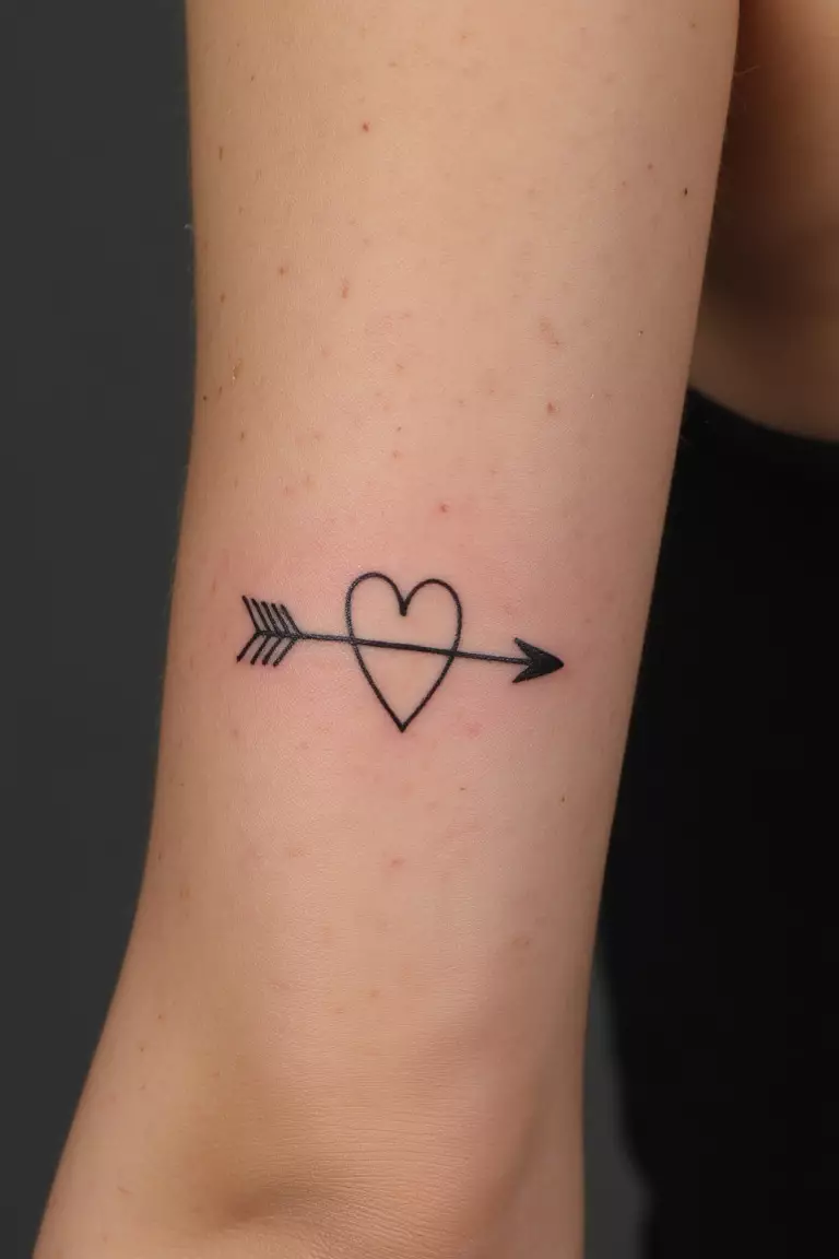 Arrow with Heart Tattoo A close up shot of woman's arm with a black ink arrow with heart tattoo, arrow piercing through a small heart