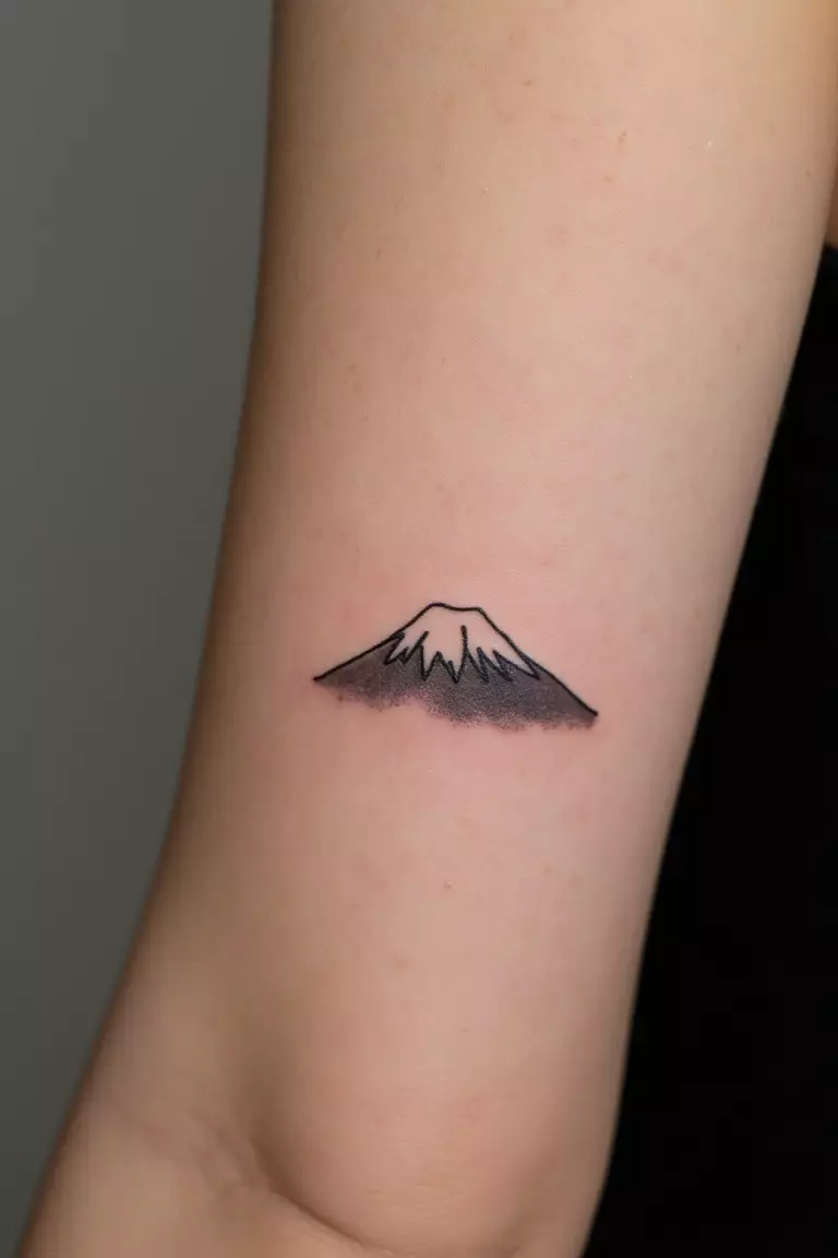 Minimalist Mt. Fuji Silhouette A close up shot of woman's arm with a black ink minimalist Mt. Fuji silhouette tattoo