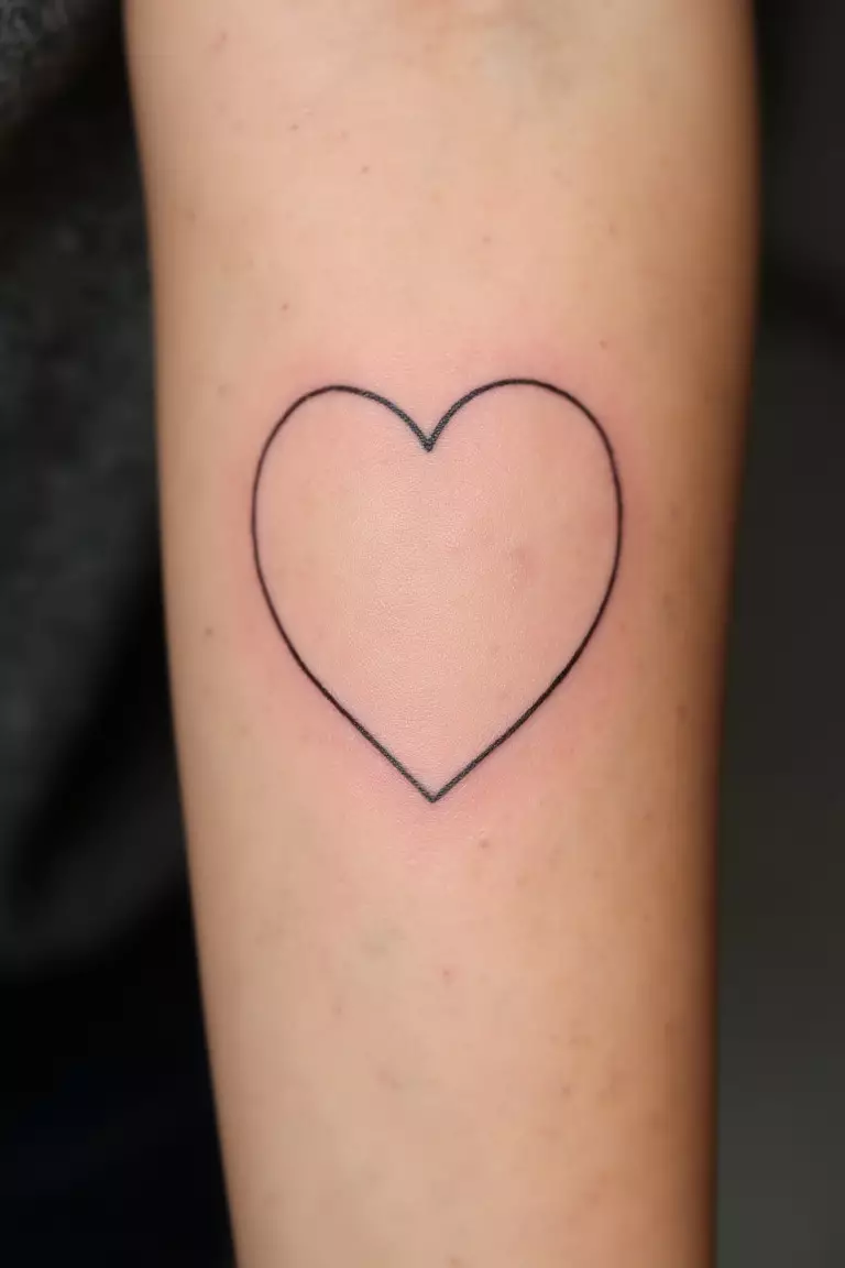 Heart Outline Tattoo A close up shot of woman's arm with a black ink heart outline tattoo, simple clean lines