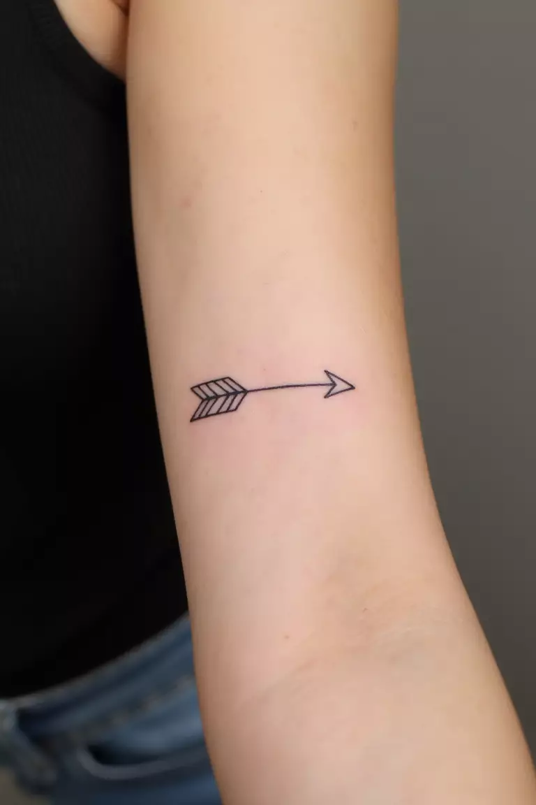 Minimalist Arrow Outline Tattoo A close up shot of woman's arm with a black ink minimalist arrow outline tattoo, just the basic contours without filling
