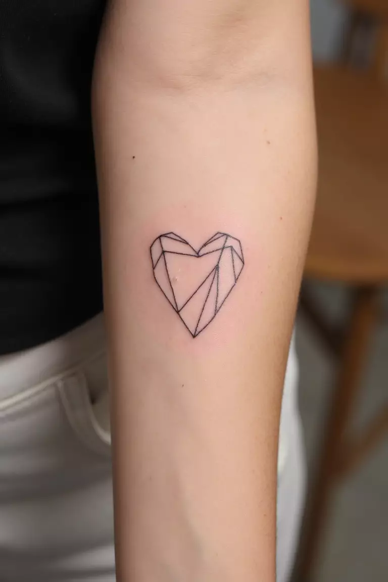 Minimal Geometric Heart Tattoo A close up shot of woman's arm with a black ink minimal geometric heart tattoo, composed of straight lines