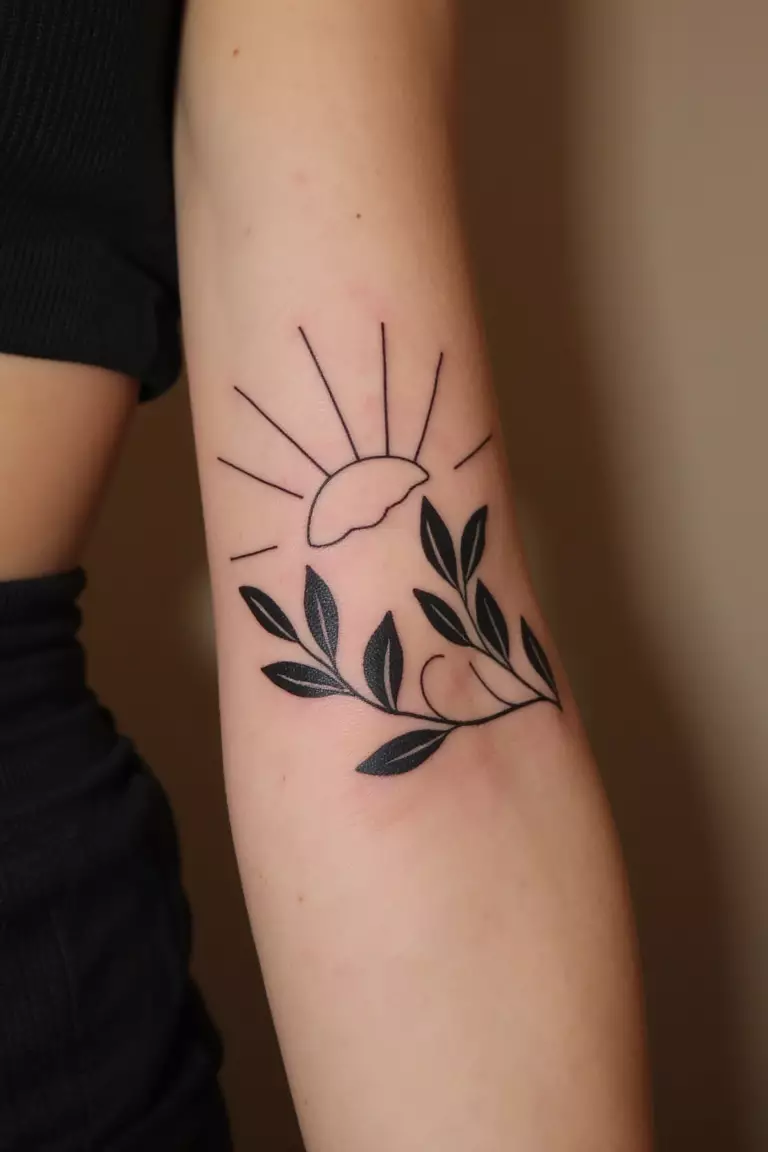 Olive Branch Silhouette Against A Sun A close up shot of woman's arm with a black ink olive branch silhouette against a sun tattoo
