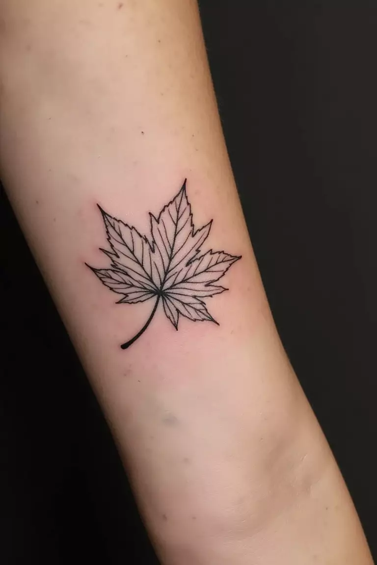Minimalist Japanese Maple Leaf A close up shot of woman's arm with a black ink minimalist Japanese maple leaf design tattoo