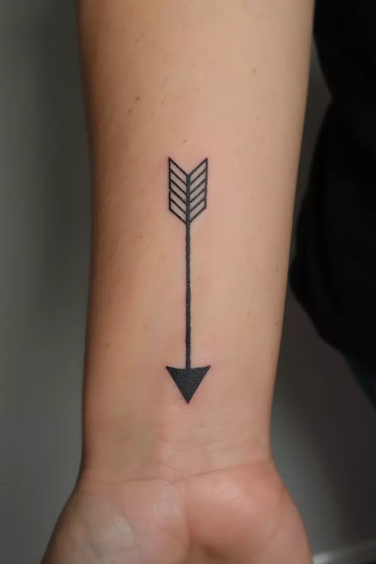Arrow Pointing Downward Tattoo A close up shot of woman's arm with a black ink arrow pointing downward tattoo, elegant and meaningful design