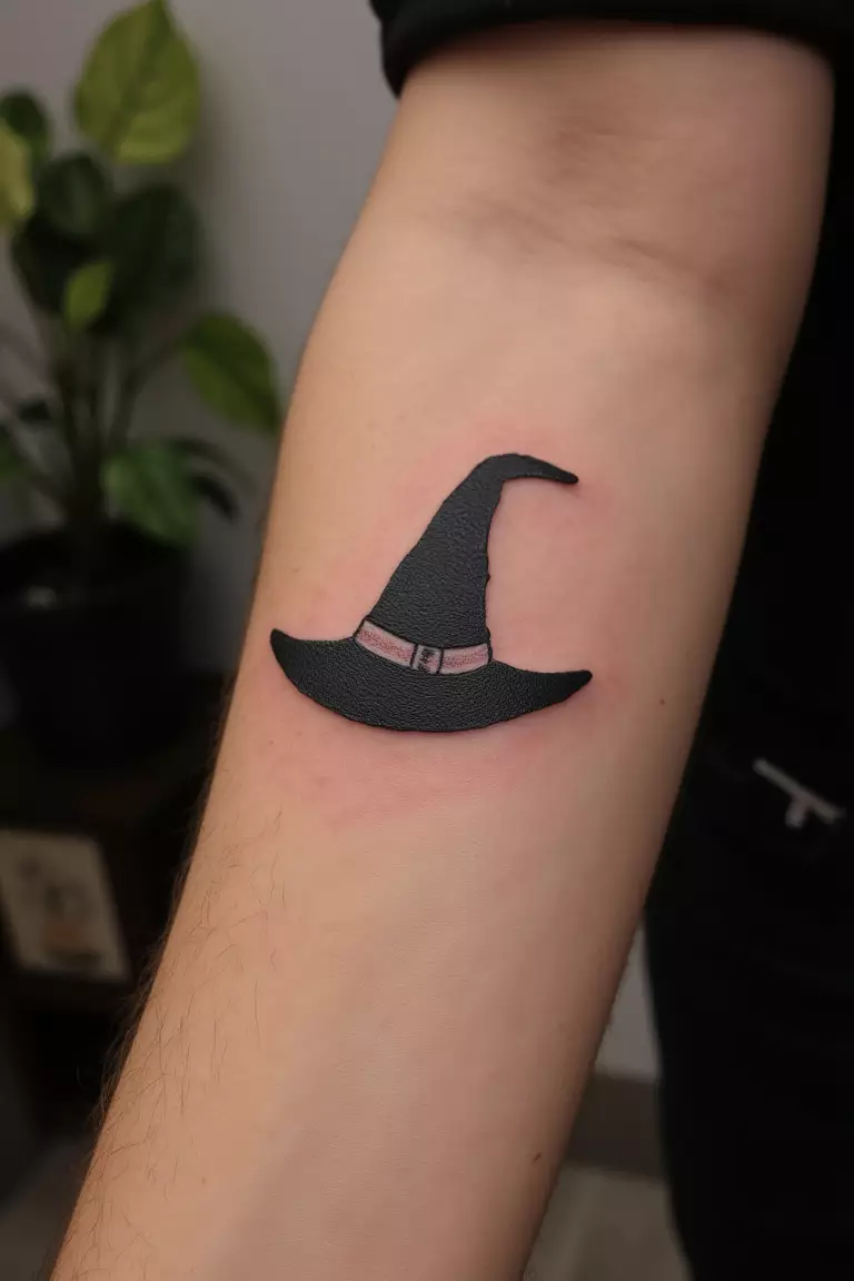 Minimal Witch Hat Tattoo A close up shot of woman's arm with a black ink tattoo of a simple witch hat.