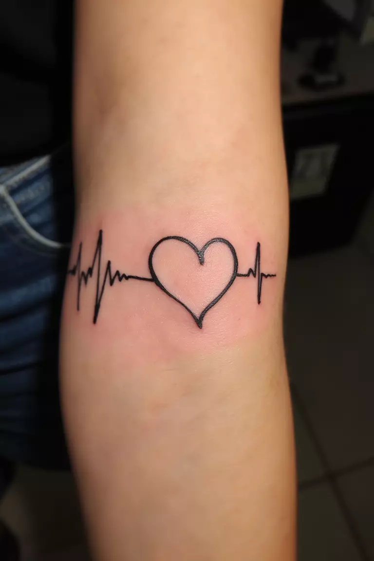 Heartbeat Line Tattoo A close up shot of woman's arm with a black ink heartbeat line tattoo, EKG rhythm forming heart shape