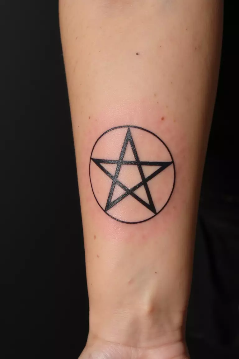 Pentagram Tattoo A close up shot of woman's arm with a black ink tattoo of a clean pentagram.