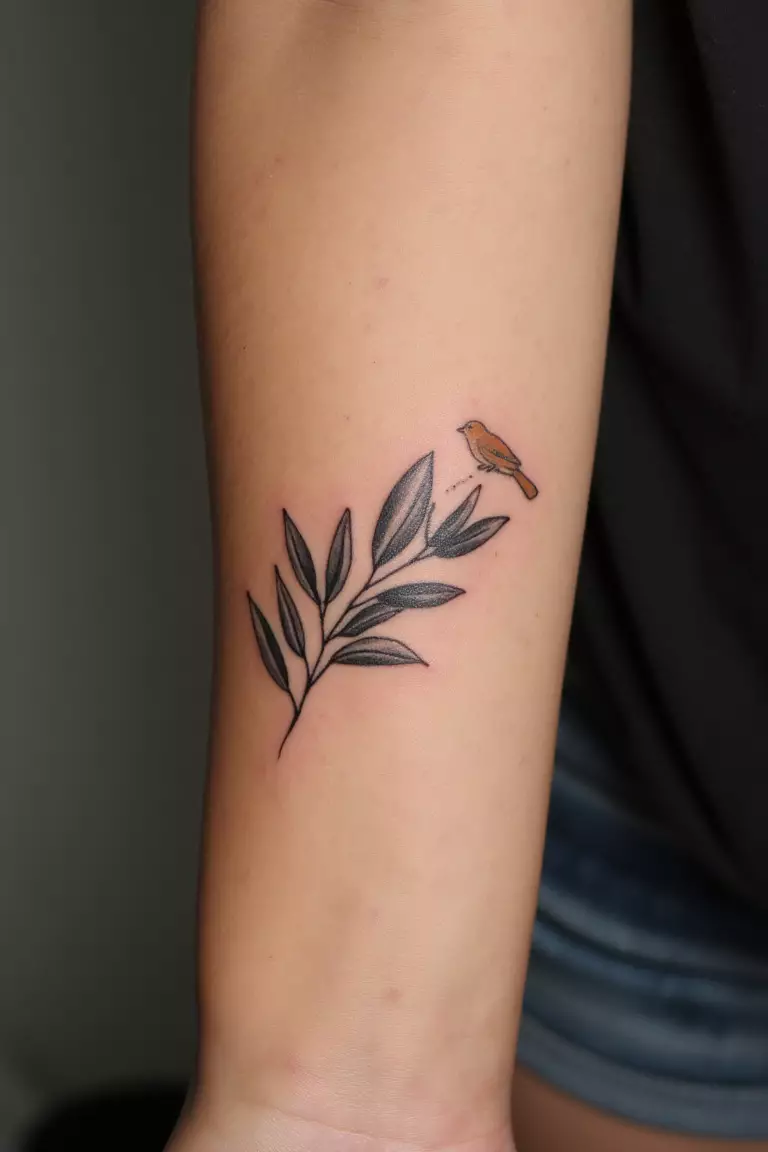 Olive Branch With A Small Bird Perched On It A close up shot of woman's arm with a black ink olive branch and a small bird perched on it tattoo