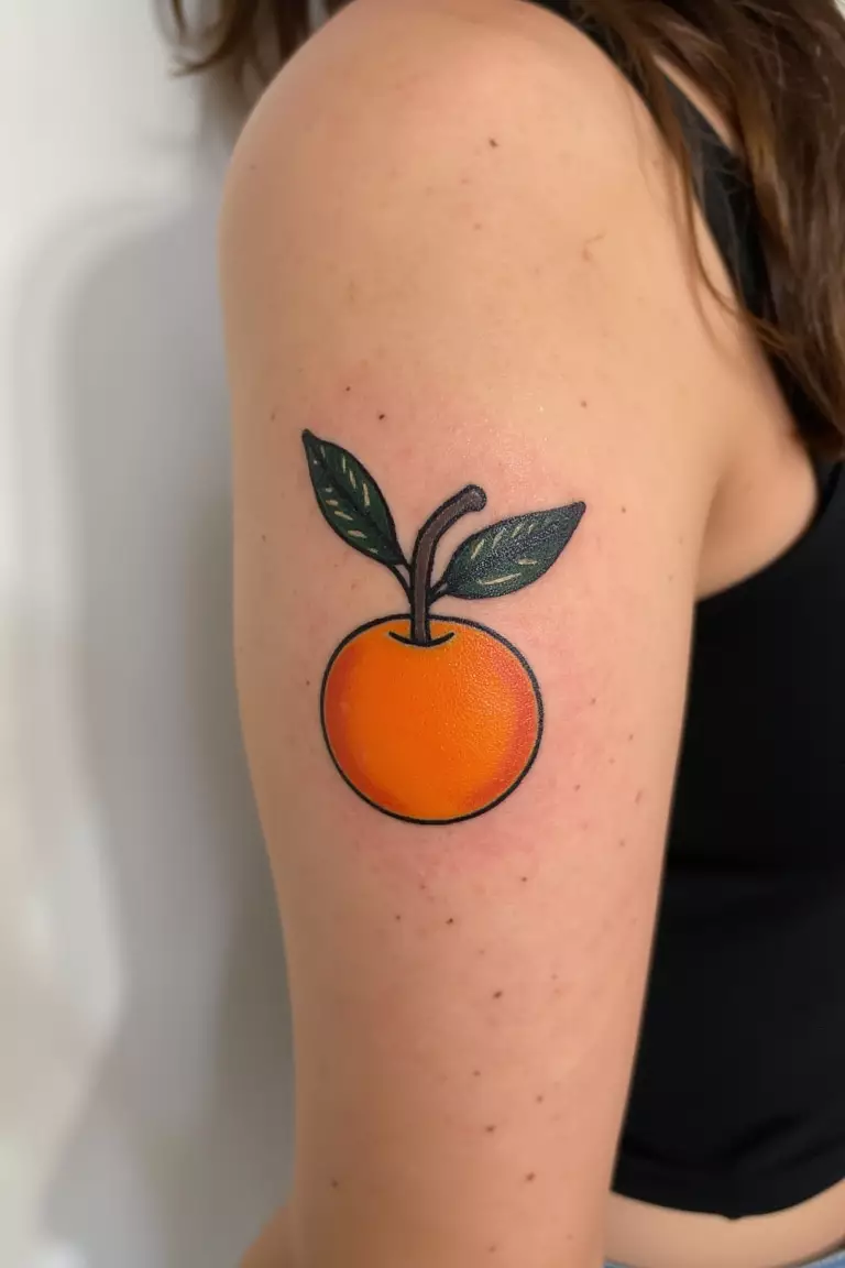 Fresh Fruit A close up shot of woman's arm with a black ink tattoo featuring a bold, bright orange fruit design, unexpected and delightfully summery.