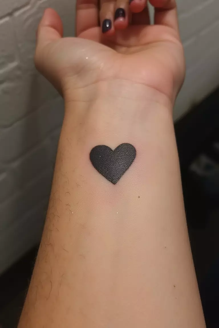 Wrist Heart Tattoo A close up shot of woman's wrist with a black ink heart tattoo, perfectly placed on pulse point