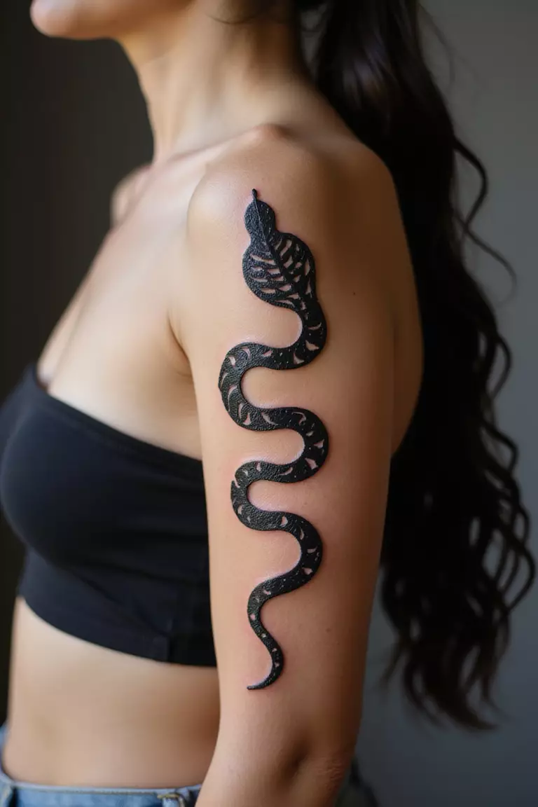 Tribal Snake A close-up shot of a woman showing her black ink tribal snake tattoo design on her arm, featuring bold, black, abstract patterns forming the snake.