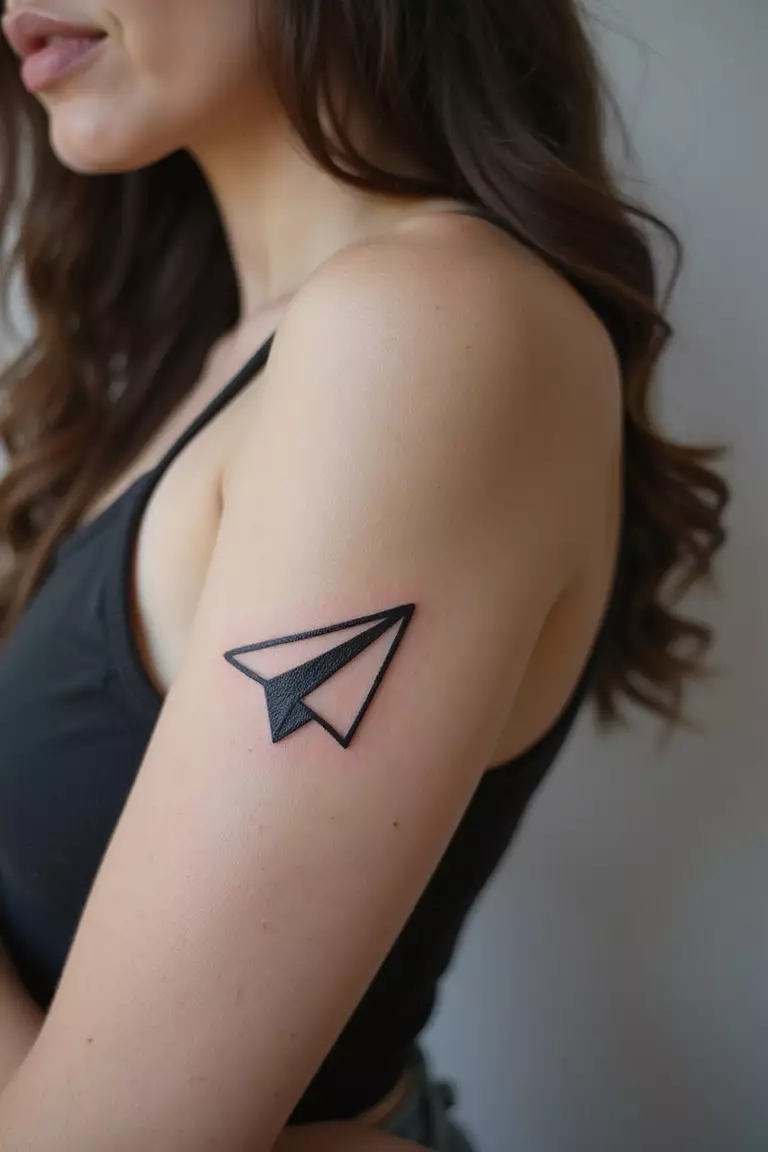 Paper Airplane A close-up shot of a woman showing her black ink paper airplane tattoo design on her arm