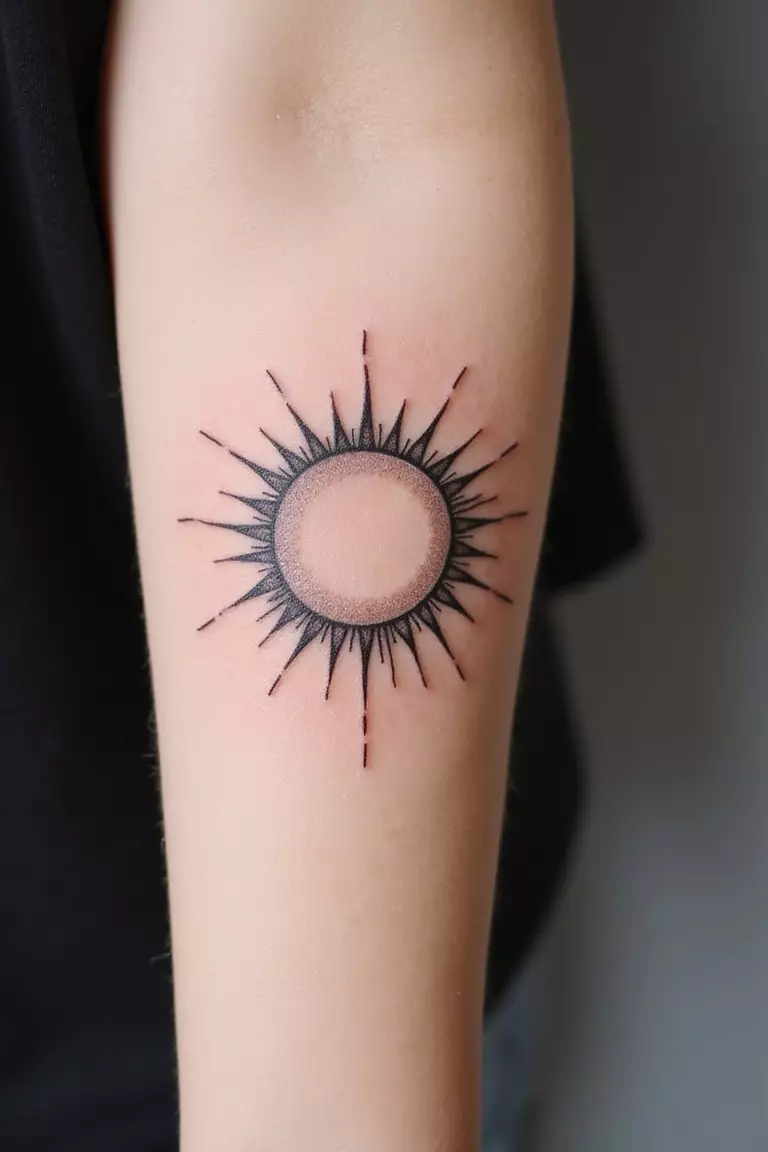A close-up shot of a woman showing her black ink minimalist sun line tattoo design on her arm