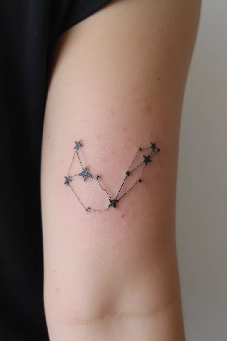 Constellation A close-up shot of a woman's arm with a black ink tattoo of the Big Dipper constellation with stars connected by fine lines.